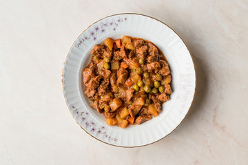 Turkish traditional tas kebab with potato, pea and tomato in a white plate