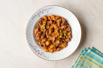 Turkish traditional tas kebab with potato, pea and tomato in a white plate