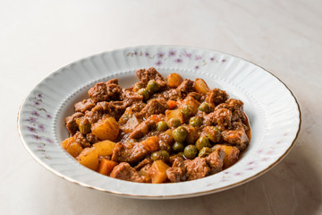 Turkish traditional tas kebab with potato, pea and tomato in a white plate