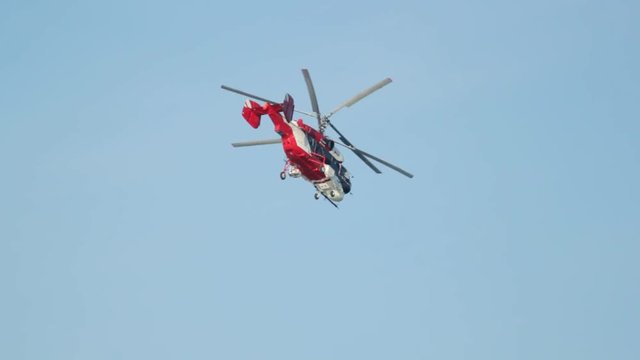 Red helicopter flying down against a clear sky without clouds