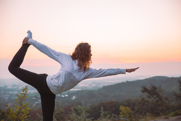 woman do yoga exercises at top of the hill on sunrise
