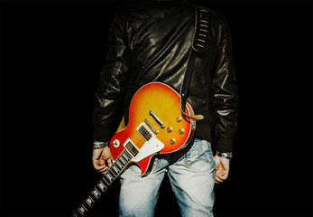 man with a guitar on his shoulder isolated on black background