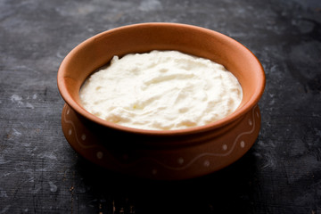 Plain curd or yogurt or Dahi in Hindi, served in a bowl over moody background. Selective focus