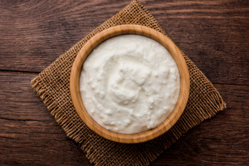 Obraz na płótnie Canvas Plain curd or yogurt or Dahi in Hindi, served in a bowl over moody background. Selective focus