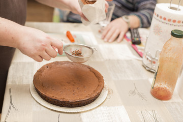 Fototapeta na wymiar horizontal image of woman's hands dusted cocoa over chocolate cake