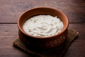 Plain curd or yogurt or Dahi in Hindi, served in a bowl over moody background. Selective focus
