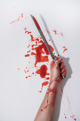 Arm of a man painted red and glitter on a white background with a knife