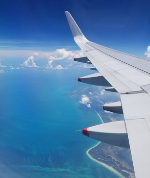Airplane wing view above the Caribbean sea.