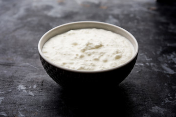 Plain curd or yogurt or Dahi in Hindi, served in a bowl over moody background. Selective focus