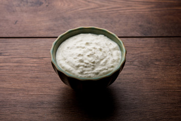 Plain curd or yogurt or Dahi in Hindi, served in a bowl over moody background. Selective focus