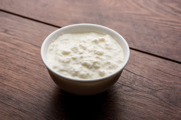 Plain curd or yogurt or Dahi in Hindi, served in a bowl over moody background. Selective focus
