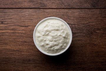 Plain curd or yogurt or Dahi in Hindi, served in a bowl over moody background. Selective focus