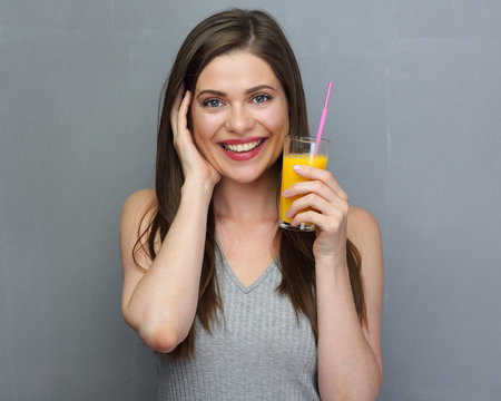 Young smiling woman holding orange juice glass with straw.