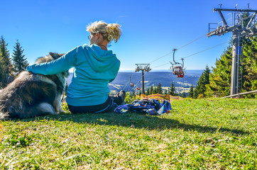 Frau sitzt in der Sonne an einer Seilbahn im Fichtelgebirge