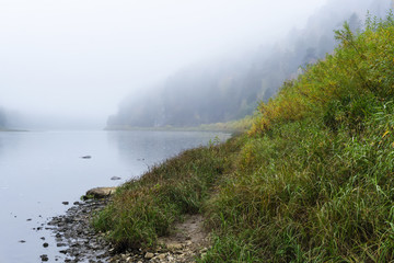 autumn river with steep wooded banks in the morning mist