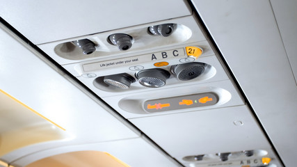 Closeup photo of buttons and lights on the ceiling above the pasenger seat in airplane