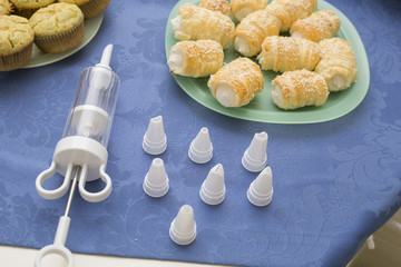 horizontal image with a top view of a plate of cannoli with filling accessories