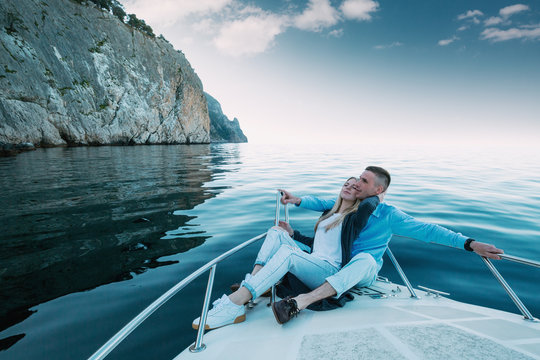 Young Couple Relaxing on a Yacht. Happy wealthy man and a woman by private boat have sea trip.