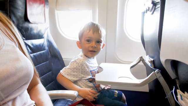Portrait of happy smiling toddler boy sitting in airplane seat