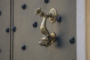 horizontal image with detail of an antique brass handle of a door in.iron