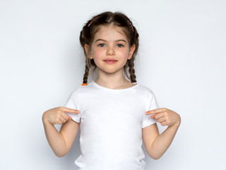 t-shirt design concept - smiling little girl in blank white t-shirt pointing at herself