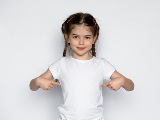 t-shirt design concept - smiling little girl in blank white t-shirt pointing at herself