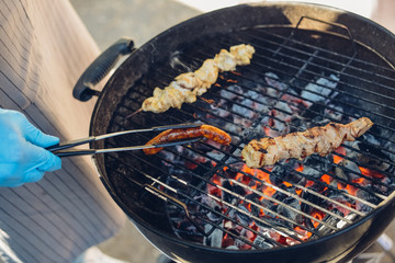 The cook fries a sausage on a grill in a street cafe