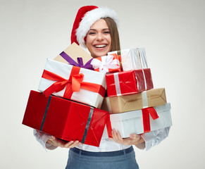 Happy woman wearing santa hat holding pile of gifts.