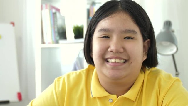 Portrait of asian preteen looking at camera with smile face, 4K Slow motion of happy asian child at home.