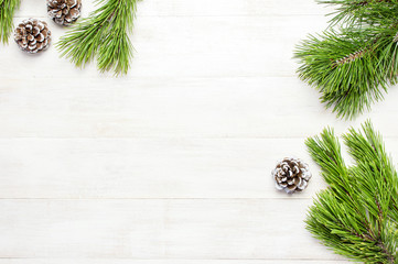 Christmas background, green pine branches, cones decorated with snow on white wooden table....
