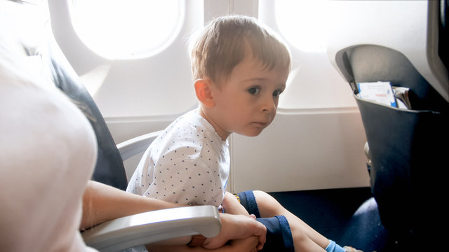 Little toddler boy holding by hand his mother during first flight in airplane