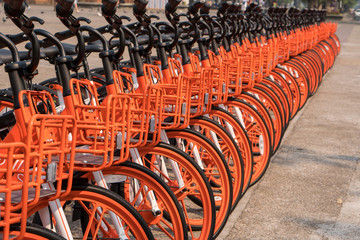Row of Orange bicycles for public use parked on the street