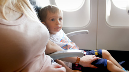 Young mother caressing and calming her little son before first flight in airplane