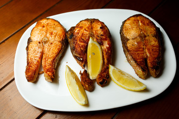 Baked fish with lemon on white plate