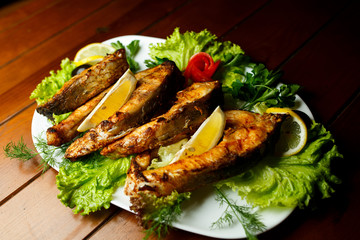 Baked fish with herbs and lemon on white plate