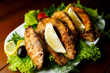 Baked fish with herbs and lemon on white plate