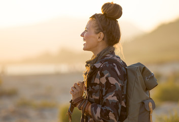 tourist woman against mountain and ocean landscape at sunset