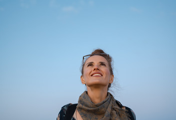 smiling tourist woman looking up at copy space against blue sky