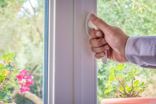 Male hand on the handle of a  window