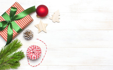 Christmas composition. New Year's wooden toys, gift, fir cones, pine branch, red ball, gift twine on white wooden table Flat lay top view copy space. Christmas winter decoration, New Year concept