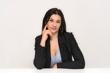 Portrait of a beautiful brunette woman on a white background with different emotions sitting at the table.