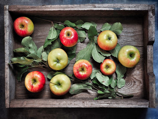 Apples with leaves in wooden box. Overhead shot.