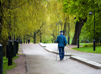 The old man goes Scandinavian walking through the autumn park