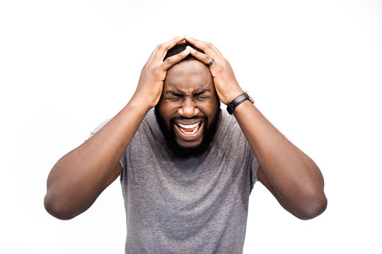 Emotional African American male closes eyes, despair, opens mouth, yells loudly, being scared of horror film. Frightened dark skinned man afraid, indignant, crying man, isolated over white background