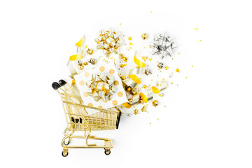 Shiny Christmas decorations and gifts with gold bows in a shopping cart on a white background....