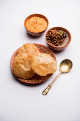 Suji/Sooji Halwa Puri or Shira Poori with black chana masala breakfast, served in a plate and bowl. selective focus