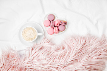 Breakfast for Valentine's day. Cup of coffee and  macaroons on bed. Flat lay, top view