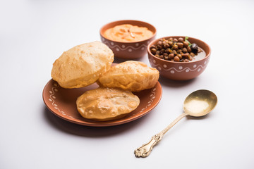 Suji/Sooji Halwa Puri or Shira Poori with black chana masala breakfast, served in a plate and bowl. selective focus