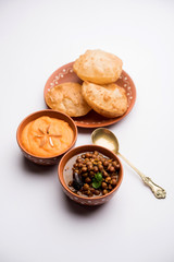 Suji/Sooji Halwa Puri or Shira Poori with black chana masala breakfast, served in a plate and bowl. selective focus