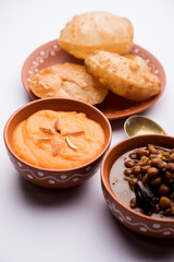 Suji/Sooji Halwa Puri or Shira Poori with black chana masala breakfast, served in a plate and bowl. selective focus